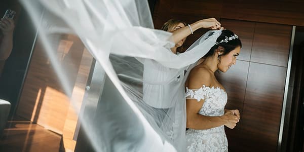 Novia con vestido de encaje y velo largo durante los preparativos